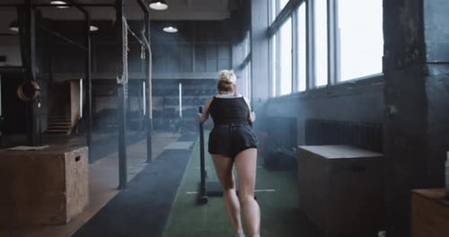 Willpower and Motivation Camera Follows Young Athletic Woman Pushing Heavy Training Sled Training in