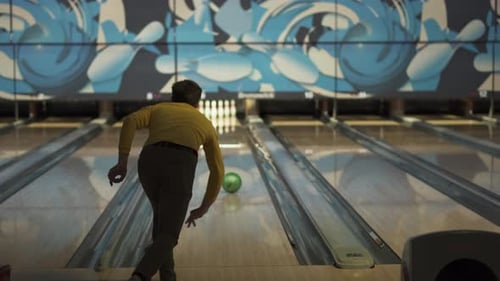 Mann wirft grünen Ball in Bowlingbahn