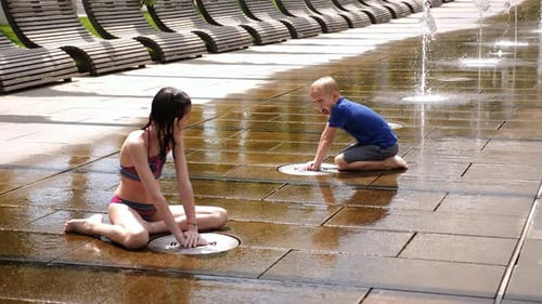 Happy Children Play in the Park with Small Streams of Water in the Fountain