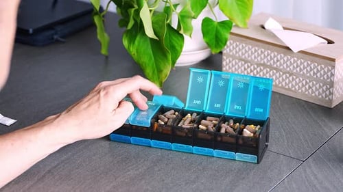 Man Sorting His Pills and Supplements Into a Weekly Pill Organizer Concept of Medication Management