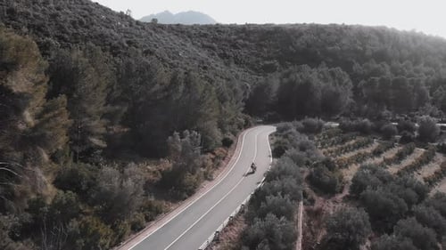 Motorcyclist riding on narrow winding mountain asphalt road