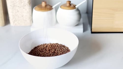 Buckwheat Being Poured into White Bowl in Kitchen
