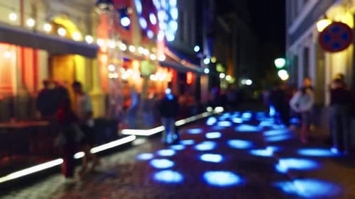 Blurred People on Lit Street at Night