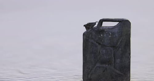 Antigua lata de combustible parcialmente sumergida en agua cerca de una zona desolada