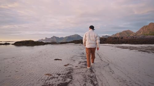 un homme marche le long de la côte au bord de la mer