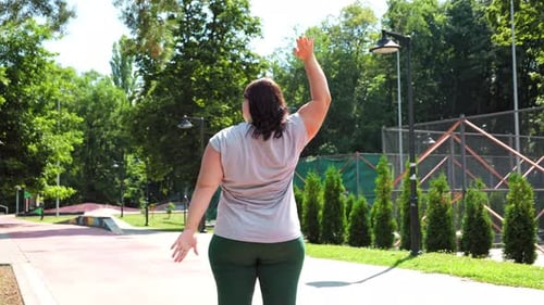 Woman Exercising and Stretching in Green Urban Park
