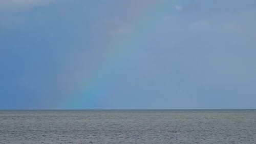 Colourful scenic rainbow over calm ocean seascape skyline