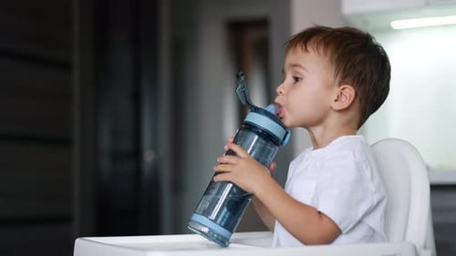 Lovely kid drinking water from a sport bottle.
