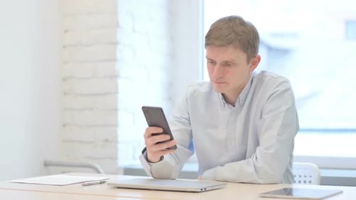 Young Adult Using Smartphone in Modern Workplace