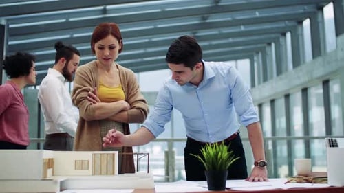 Young architects discussing house design model in modern office space