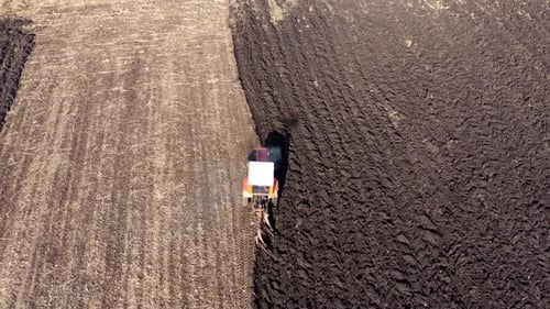 Slow motion aerial view of spring agricultural field work, tractor with seeder sow seeds in ground