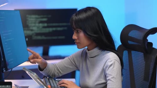 Asiatische Programmiererin arbeitet spät in der Nacht am Computer