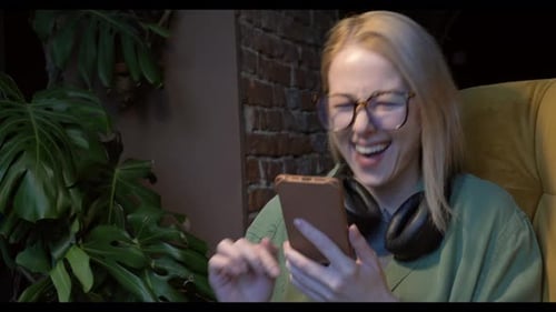 Woman Laughing Using Phone Indoors at Night