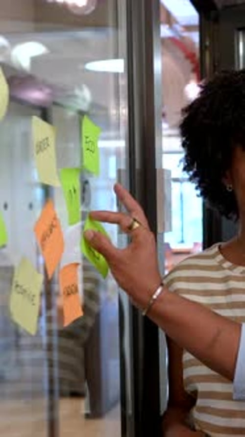 Diverse Team Brainstorming Ideas with Sticky Notes on a Glass Wall