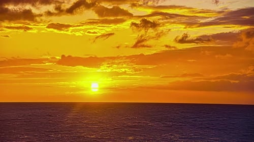 Time lapse shot of golden sunrise over tranquil Ocean with clouds at sky in motion