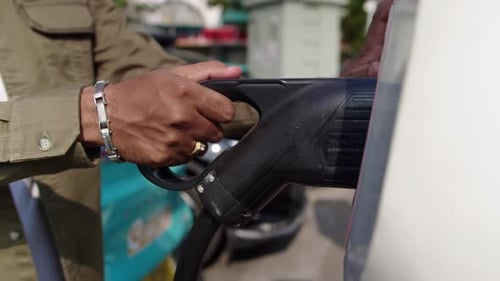 Hände des Fahrers, der das Kabel aus dem Ladeanschluss an der EV-Ladestation zieht