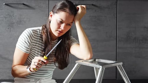 Frustrated Young Woman Trying to Assemble a Chair with Tools on the Floor Concept of Difficulty and