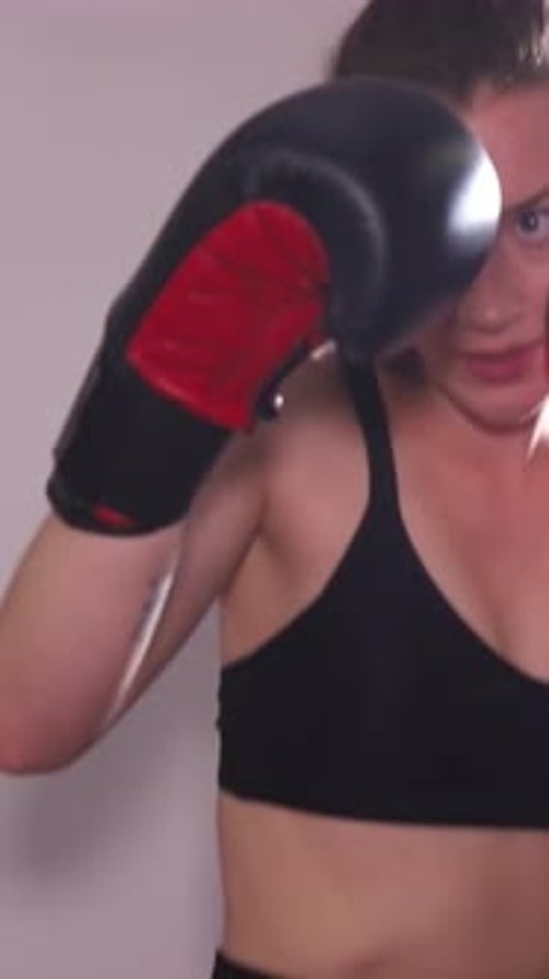 Woman Punches Boxing Bag During Intense Gym Workout