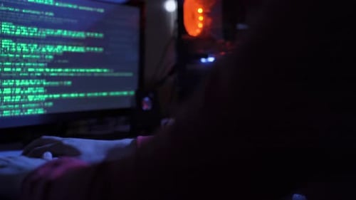 Person Coding at Computer in a Dark Room