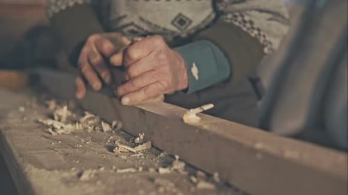 Senior Craftsman Working with Planer on Wooden Pole in His Workshop