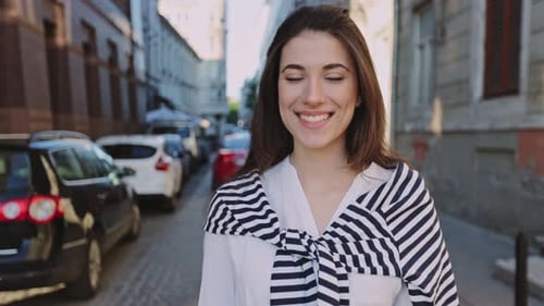 Portrait of the Beautiful Caucasian Woman with Long Hair Standing on the Warm Spring City Street