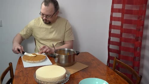 Die Kuchen mit Sahne bestreichen Der Mann macht zu Hause einen Waffelkuchen mit Kondensmilch und süßem Essen