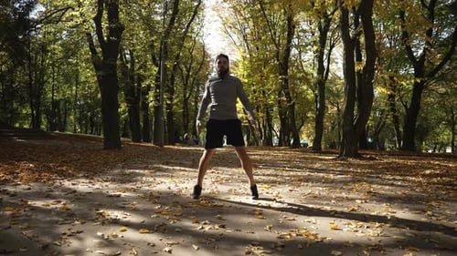 A Young Athlete is Doing Warmup Before Training in an Autumn Park