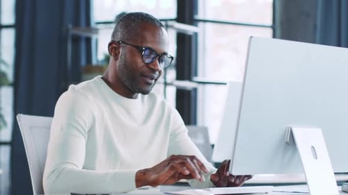Business Professional Focuses on Work at a Modern Office Desk in a Bright Environment
