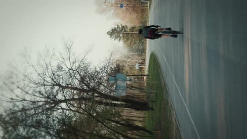 Male pro cyclist in black cycling apparel riding on road bicycle. Vertical video