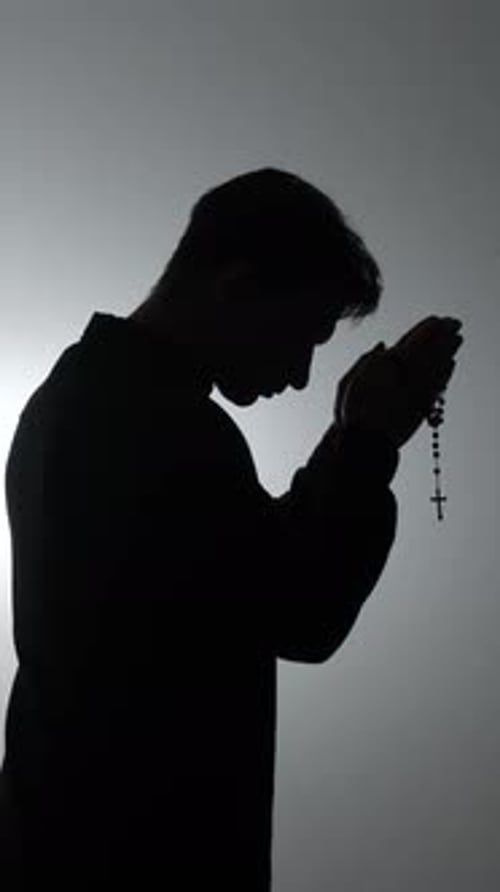 Man Silhouette Praying with Rosary Beads in Studio
