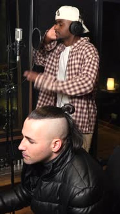 Singer recording music in studio with producer