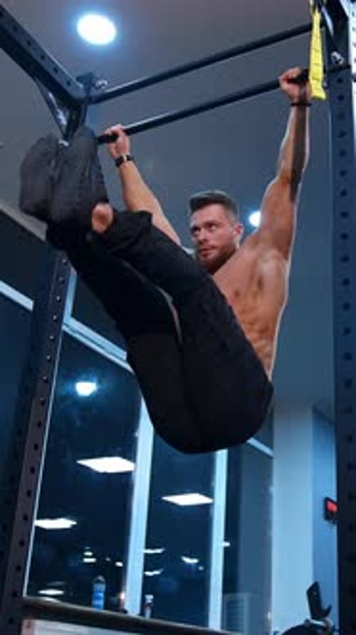 Strong athlete doing pull up. Muscular man doing exercises on horizontal bar in gym