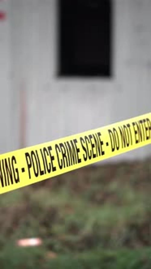 Vertical View of Police Crime Scene Tape Ribbon in Front of White Living Container, Close Up