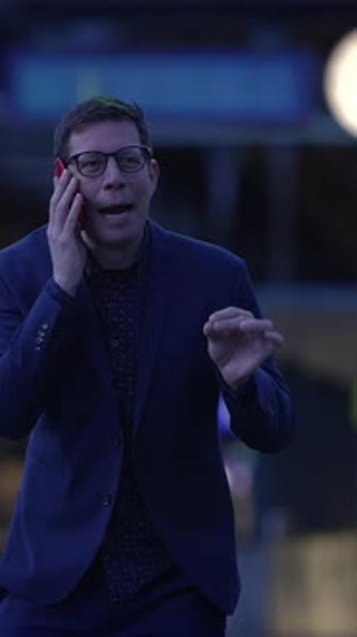 A Man is Engaging in an Animated Conversation During the Night in the City Environment