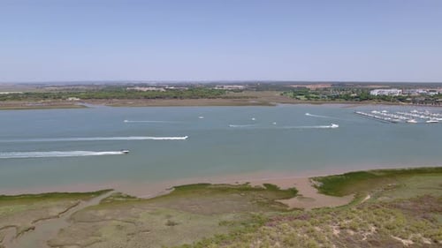 Motor boats sailing and white wakes in the estuary. Panoramic travelling aerial view over boats in t