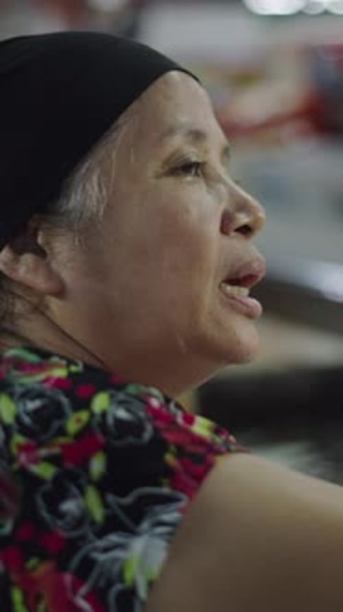 Senhora asiática madura de um peixeiro com contas na mão faz um pagamento a outra pessoa em um