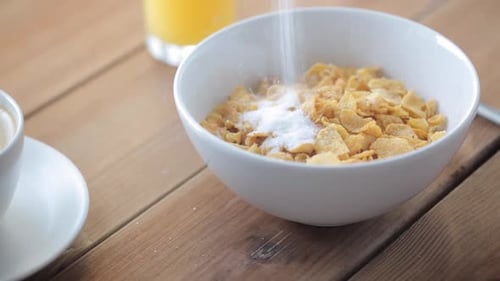 White sugar cascade sweetening corn flakes at a breakfast table