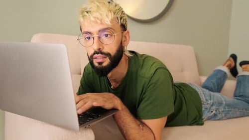 Man Using Laptop While Lying on Couch