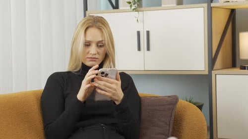 Woman Using Phone with Concerned Expression Indoors