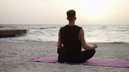 Man Meditating on Beach at Sunrise