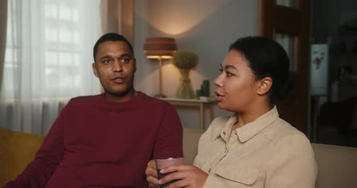 Man and Woman Talking on Couch Indoors