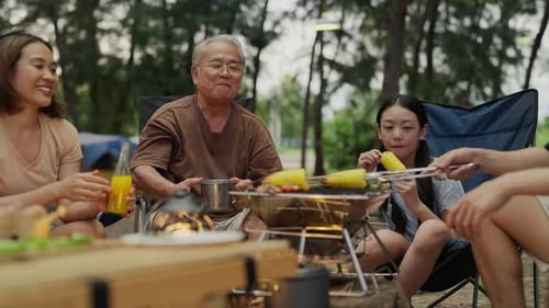 Família asiática feliz com festa de churrasco na praia de acampamento juntos