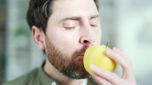 Bearded Man Eating a Yellow Apple Close-up