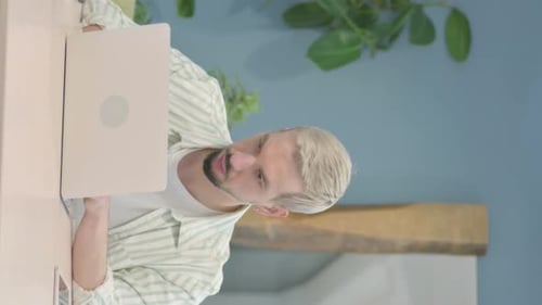 Man Works on Laptop at Desk at Home