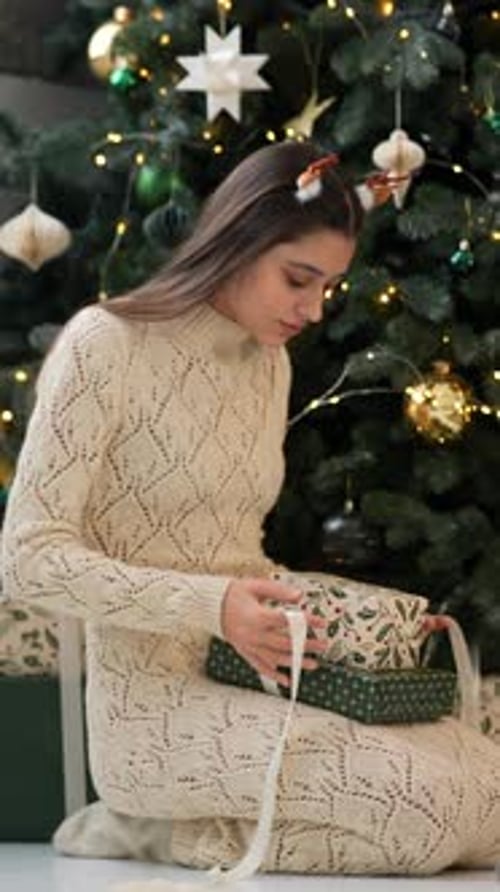 Young Woman Tying Ribbon on Christmas Gifts