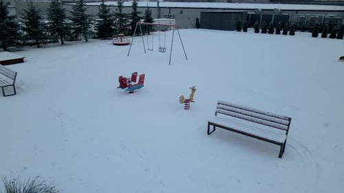 Aerial Reveal Of A Dog Strolling On Snowy Playground In Lubawa, Poland, During Winter.