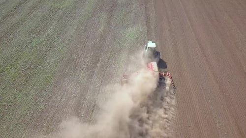 Top Down Aerial View of Green Tractor Cultivating Ground and Seeding a Dry Field