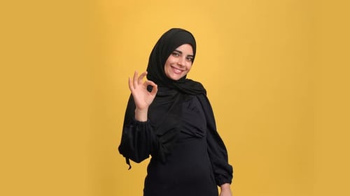 Smiling Turkish Young Woman in Black Hijab Showing Ok Okay Good Cool Gesture Posing Isolated Orange