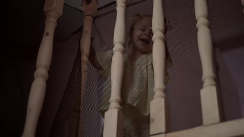 Lowangle View of Cheerful Curious Toddler Girl Fooling Dancing Through Wooden Stair Railing Secured