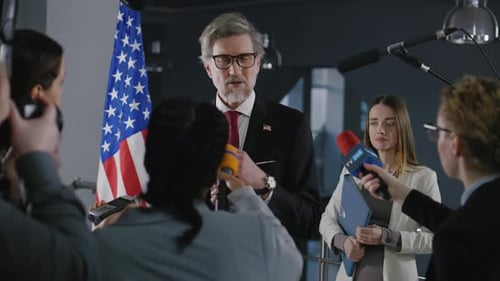Official Speaks at Press Conference with American Flag